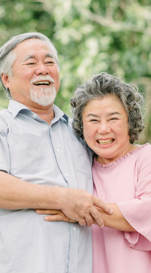 Happy senior couple holding each other in park Happy Asian senior couple laughing and smiling while holding each other outdoor in the park.